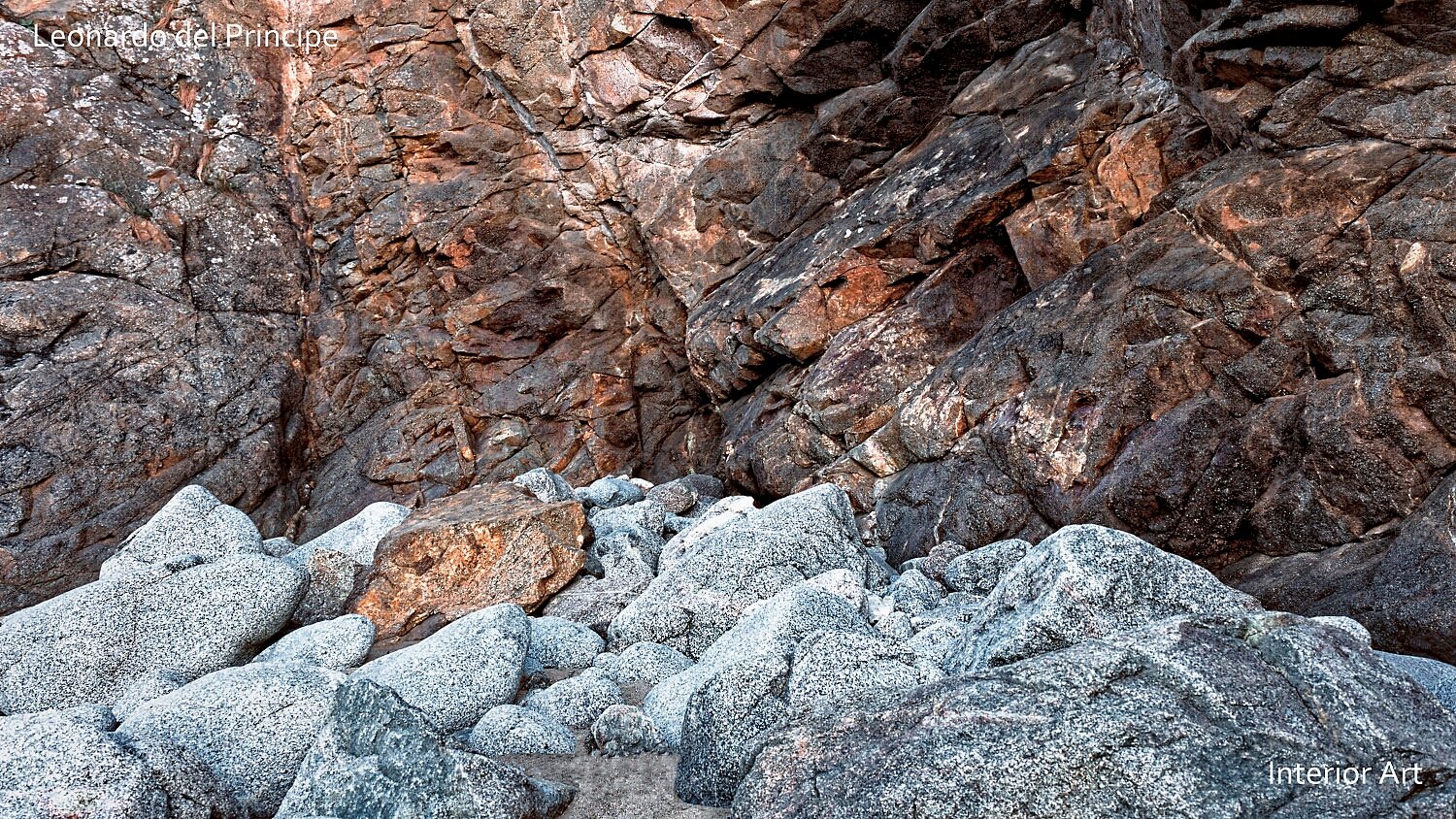 SMPC04 Rocky terrain with large, rugged boulders dominating the foreground and midground, against a backdrop of a steep, textured rock face.