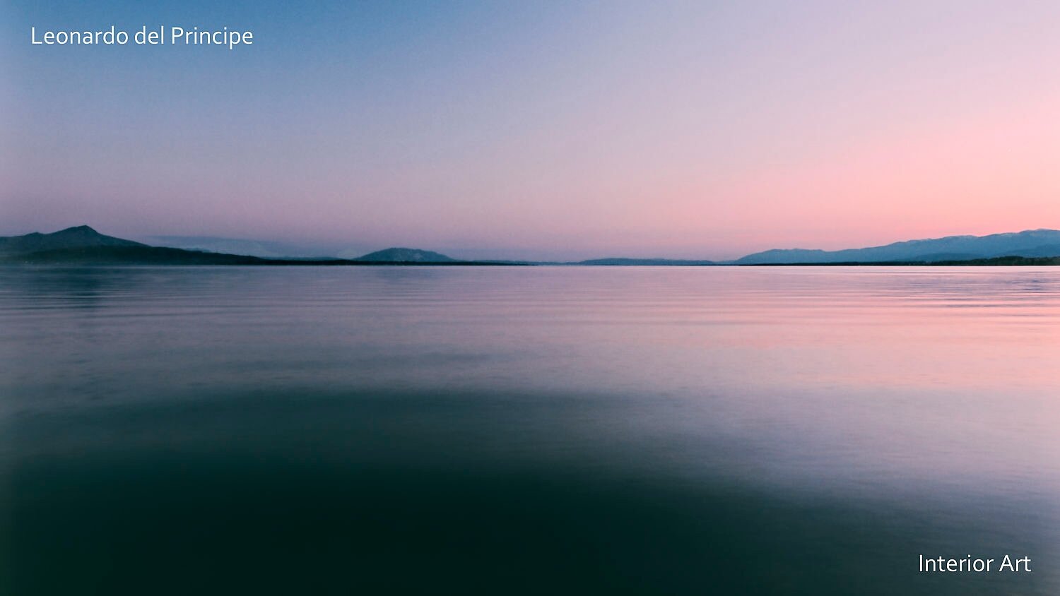 WFNF03 Tranquil Geneva lake scene at dusk with soft pink and purple hues reflecting on calm water. Distant mountains form a serene, peaceful horizon.